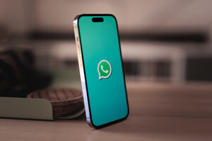 Ein Smartphone, das auf einem Tisch steht. Das Smartphone-Display zeigt symbolisch das WhatsApp-Logo an.